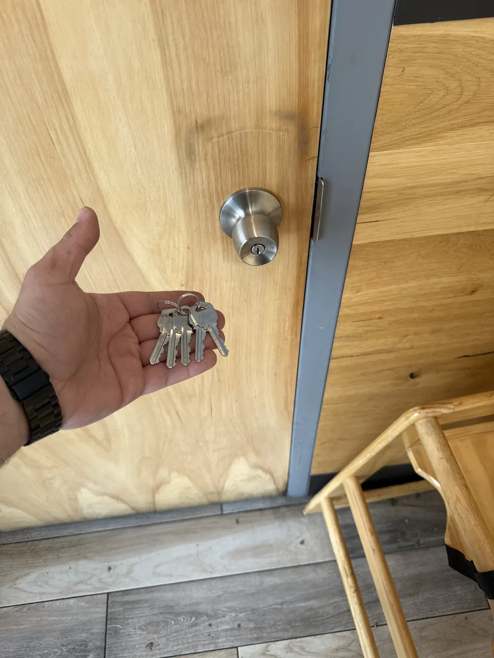 A set of keys held beside a residential door lock